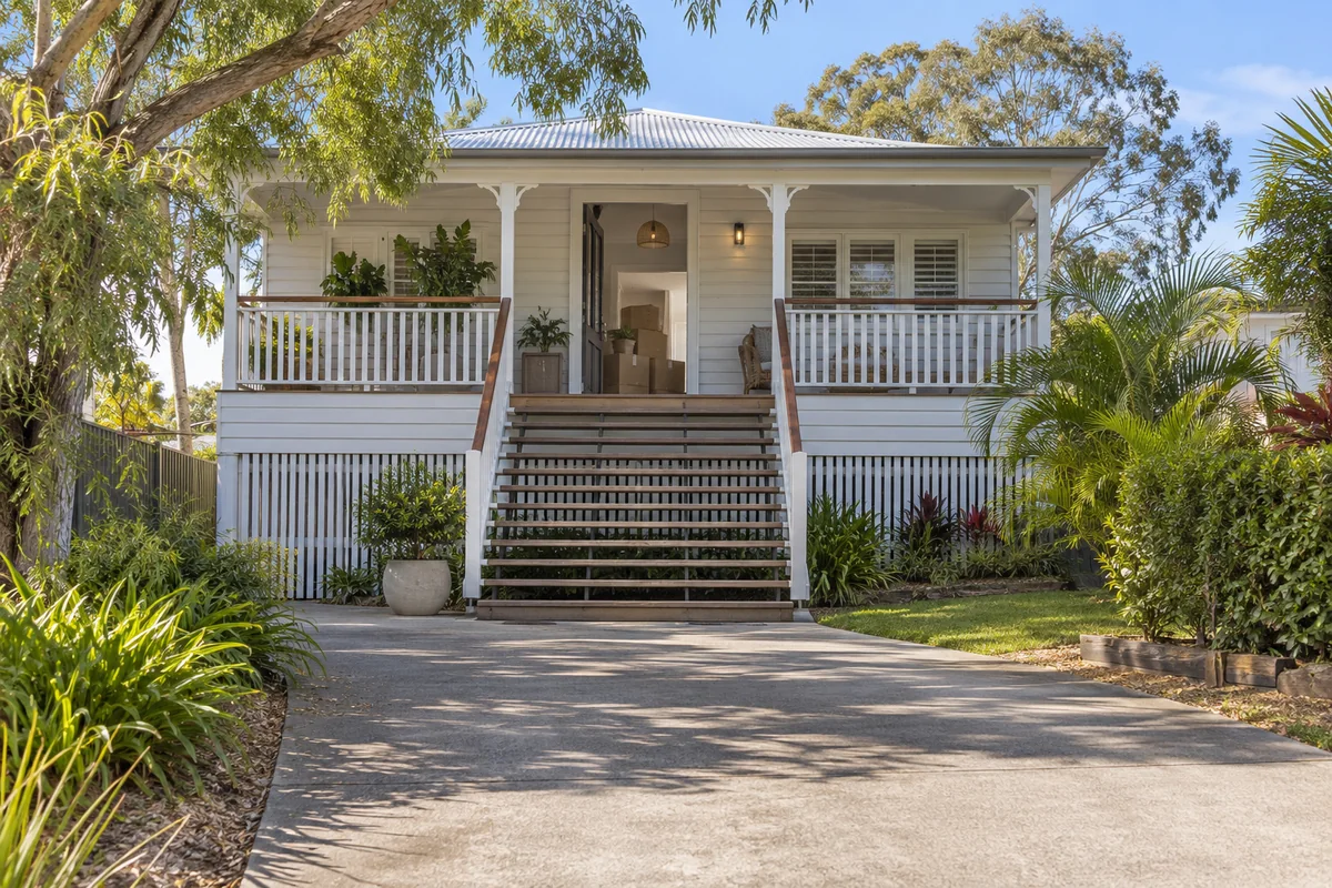 Queensland-style home with exterior stairs and a clear paved approach